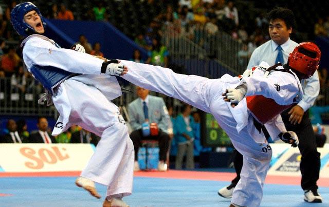 14 Jul 2007, Rio de Janeiro, Brazil --- Canadian Jocelyn Addison (L) receives a back kick of his rival Gabriel Mercedes (R), of Dominican Republic, during their taekwondo fight in the men's under 58 kg preliminary event of the XV Panamerican Games Rio 2007 at the Riocentro Sports Complex in Rio de Janeiro, Brazil. --- Image by © Sebastiao Moreira/epa/Corbis