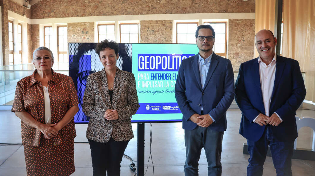 Four professionals stand in a bright room with a screen reading 'GEOPOLÍTICA' behind them, posing for a photo at a panel event.