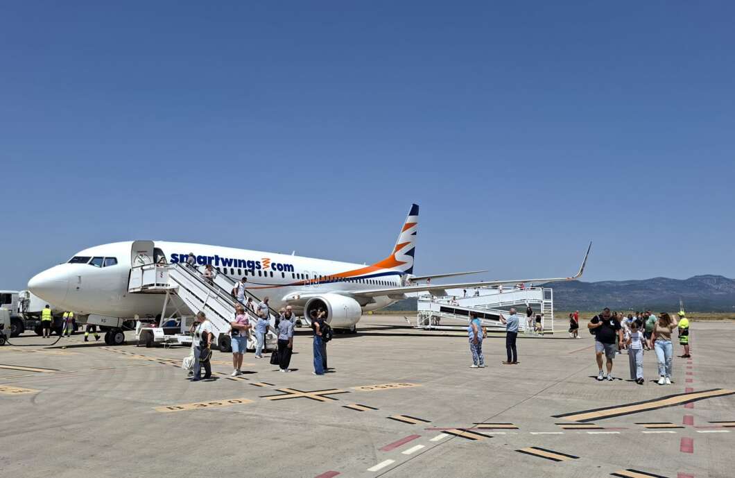 A SmartWings airplane on the tarmac with passengers boarding via mobile stairs on a sunny day at the airport.