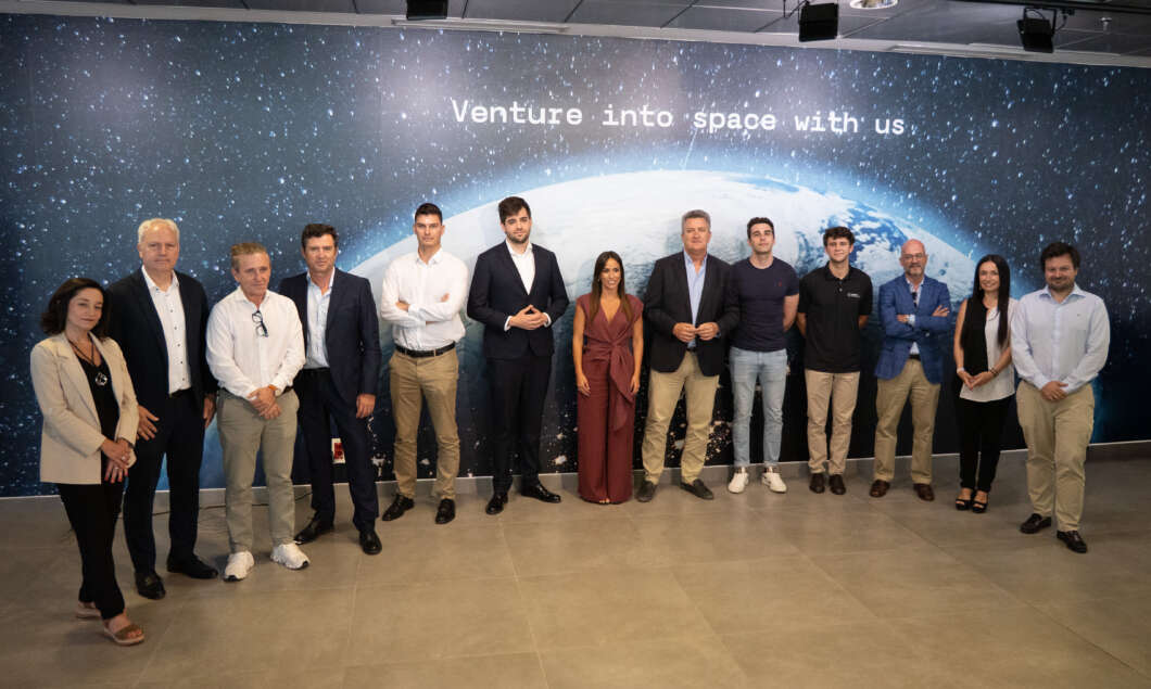 Group of twelve professionals posing in front of a space-themed wall with the slogan 'Venture into space with us'.