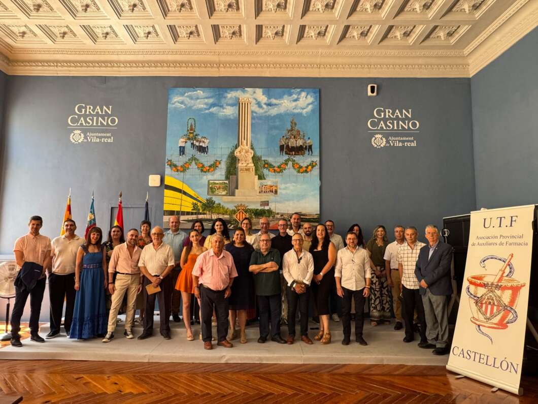 Group of about 25 people standing on a stage inside a casino, with Gran Casino Vila-real signs and a large mural behind them.