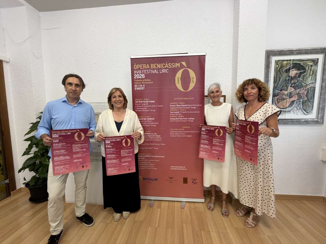Four adults stand indoors, each holding pink festival flyers in front of a large burgundy event banner.