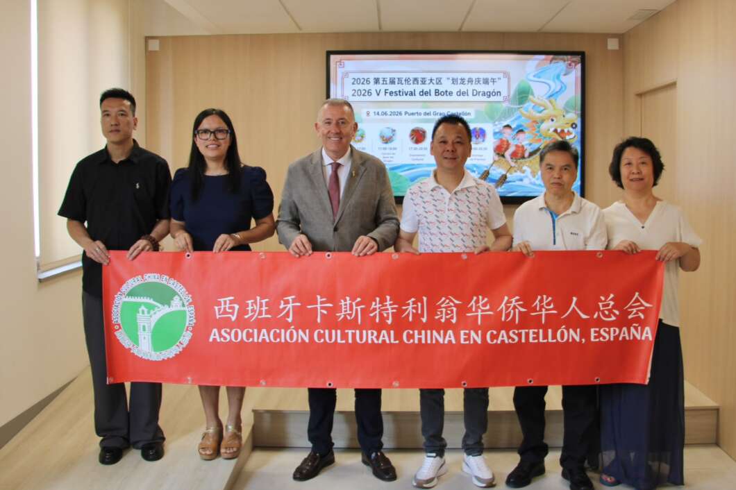 Six people stand in a hallway holding a red banner that reads 'Asociación Cultural China en Castellón, España' with a green circular emblem on the left.