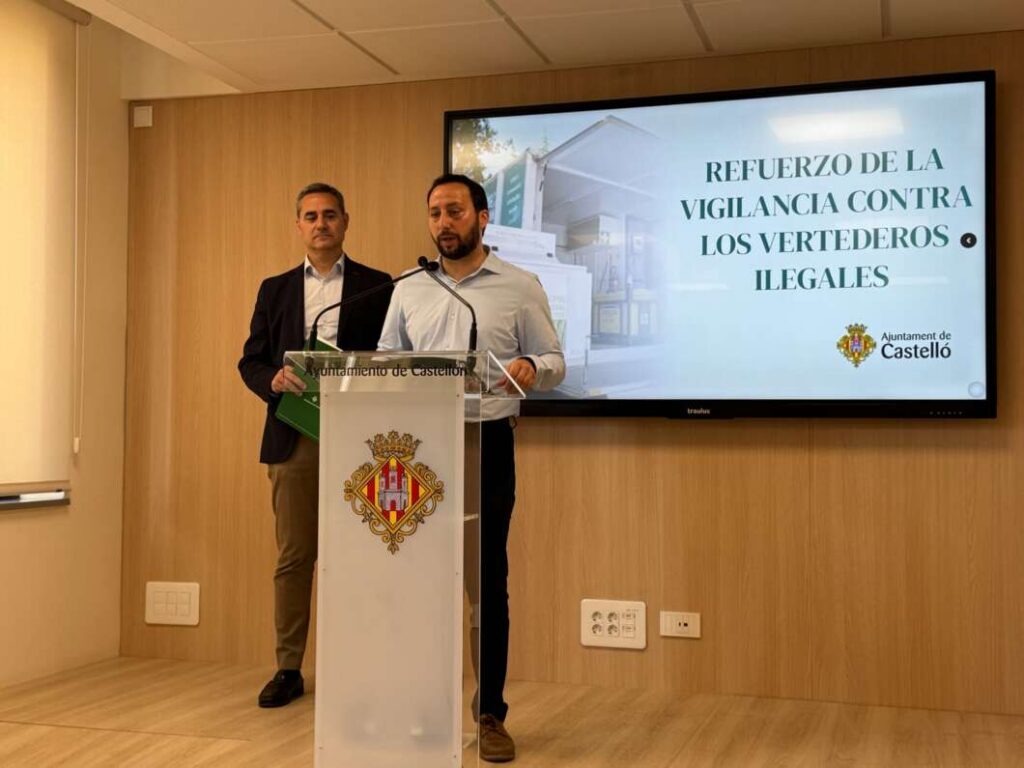 Two men speak at a podium featuring the Castelló city crest, with a slide about strengthening vigilance against illegal dumping on the screen behind them.