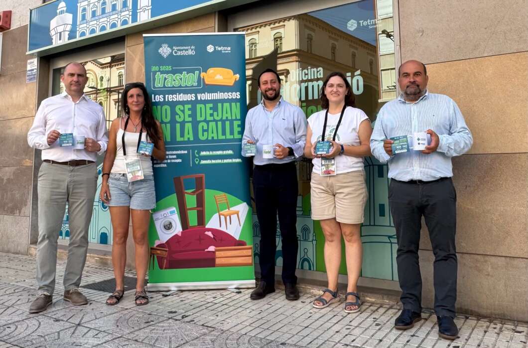 Five people pose outside a building holding campaign flyers for a city bulky-waste program, with a colorful banner behind them on the wall.