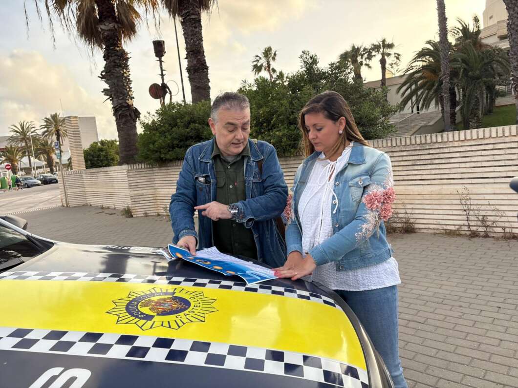 Two adults stand beside a police car, reviewing a brochure on the hood of the car in a sunny outdoor setting with palm trees.