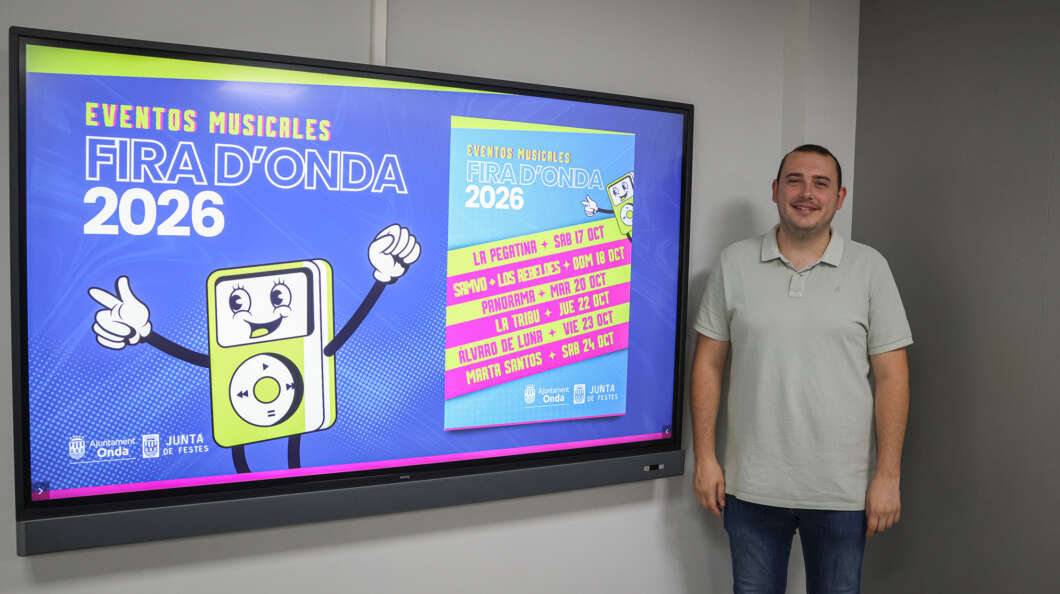 Man stands beside a large digital screen displaying a vibrant poster for 'Fira d'Onda 2026' with a cartoon music player character on the left side.