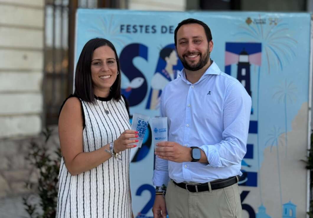 Two adults smile at a festival, each holding a blue paper cup, with a blue event banner in the background.