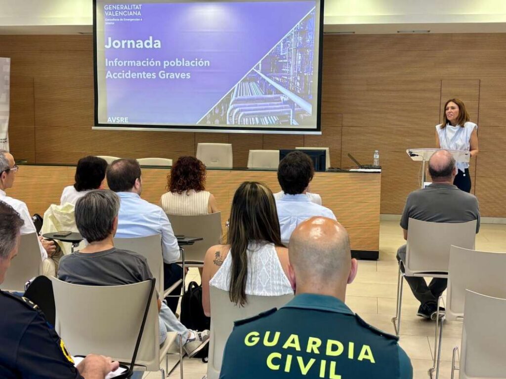 Speaker at a lectern addressing an audience; slide reads 'Jornada Información población Accidentes Graves'.