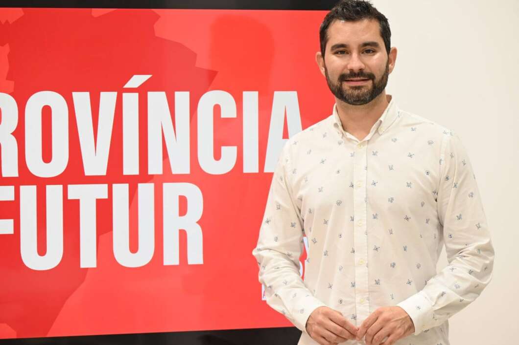 Man with dark hair and beard in a white patterned shirt stands beside a bright red banner with large white text reading 'PROVÍNCIA FUTUR'.