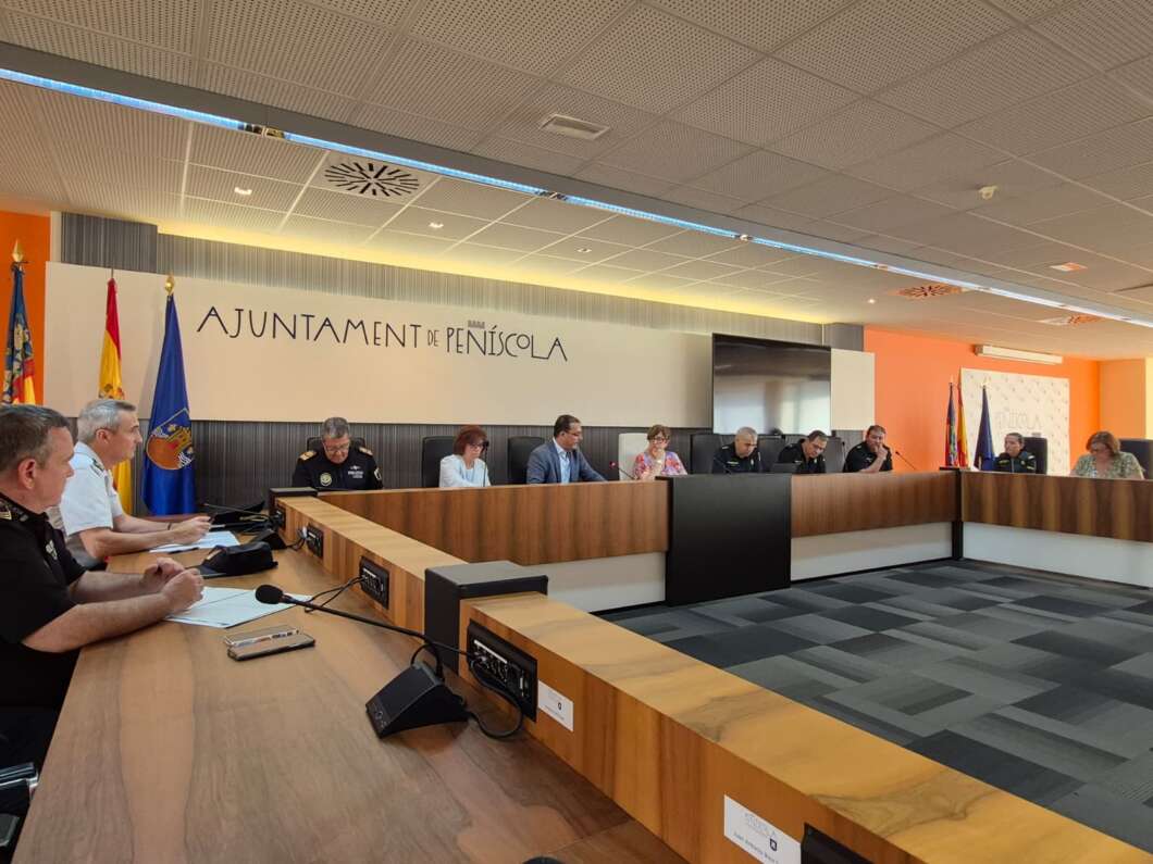 Council chamber meeting in Peníscola with officials seated at long wooden desks under 'Ajuntament de Peníscola' signage.