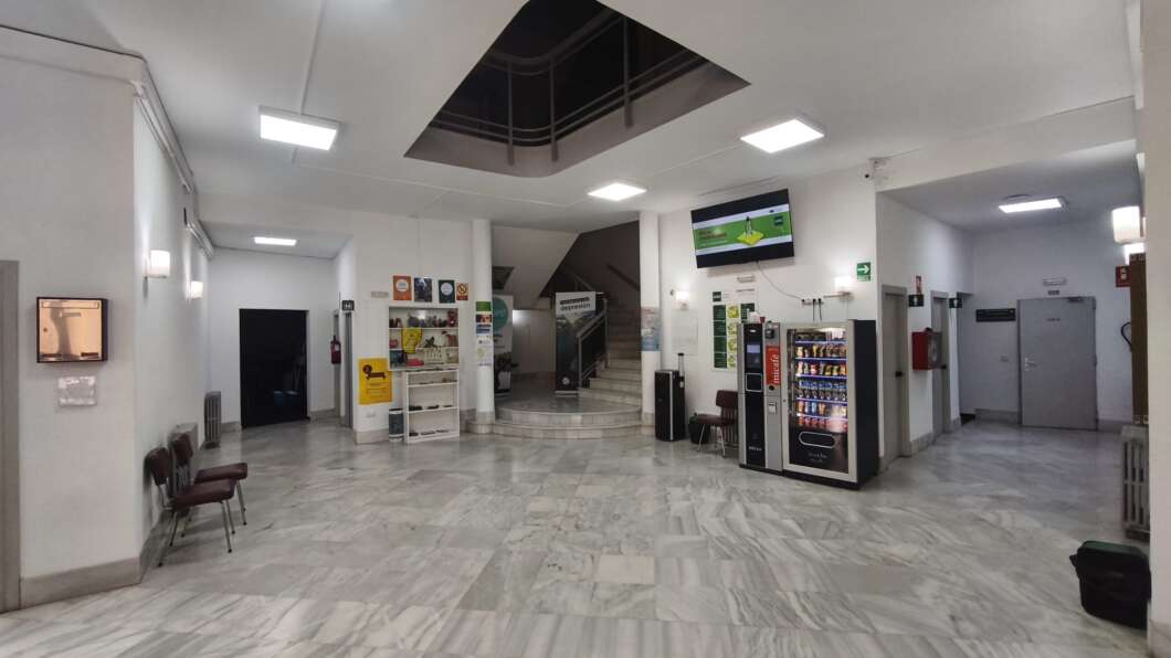 Spacious marble-floored lobby with a vending machine cluster on the right, a central staircase, and ceiling light panels.