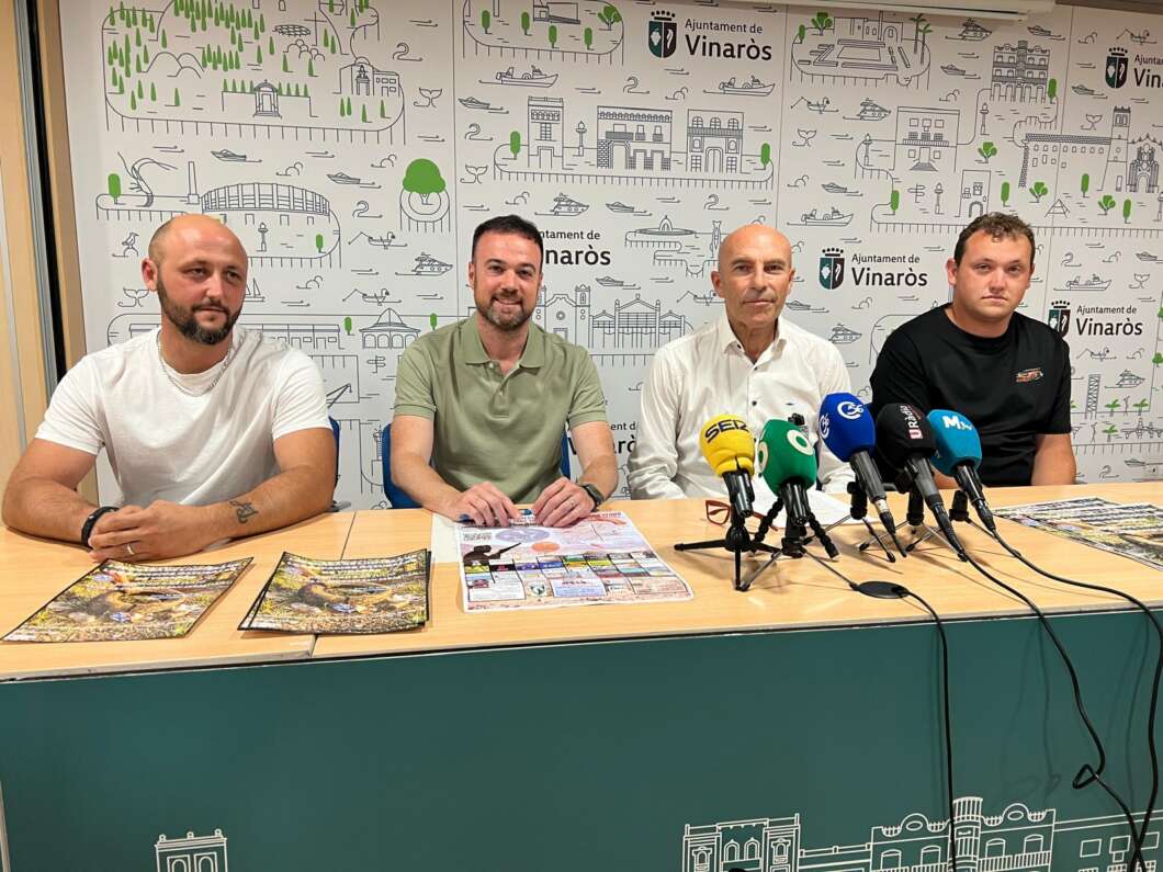 Four men sit at a press conference table with multiple microphones in front of them; backdrop shows Vinaròs branding and illustrations.
