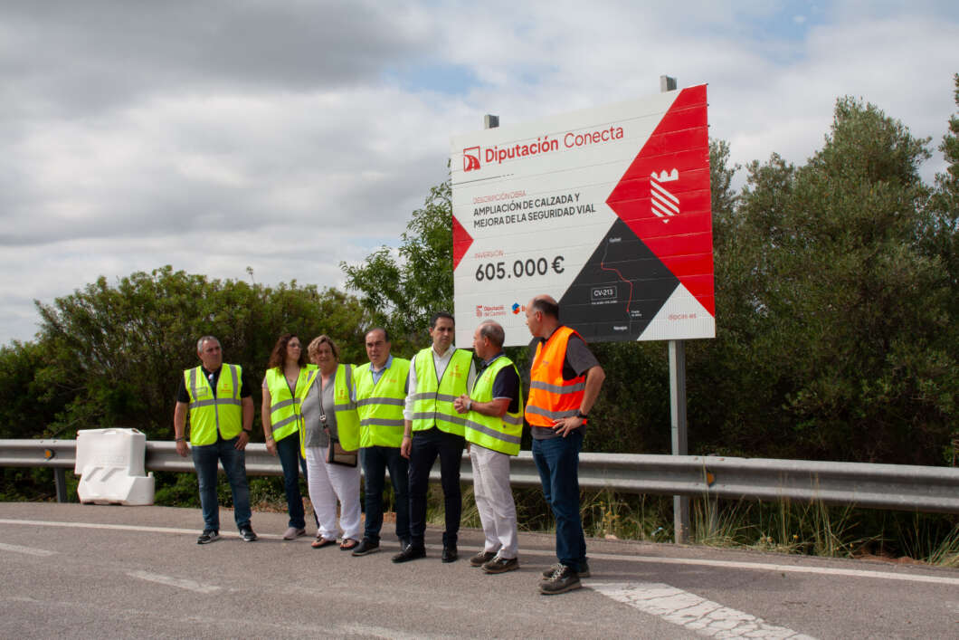 Seven people in neon safety vests stand along a highway beside a large billboard reading Diputación Conecta and 605.000 €.