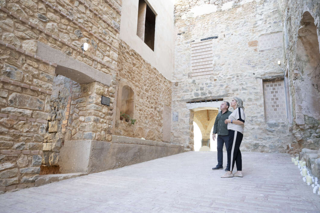 Two adults stand together in a narrow stone alley, looking at a historic building and archways.