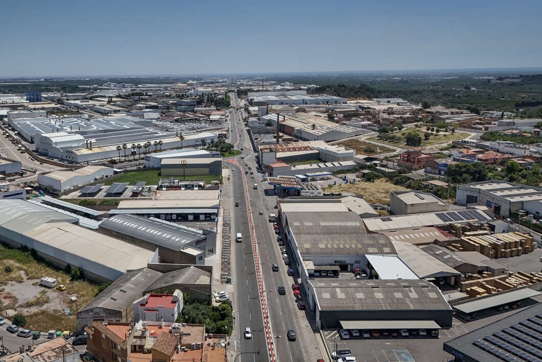 Aerial view of a busy industrial district with a central road flanked by warehouses and loading docks.