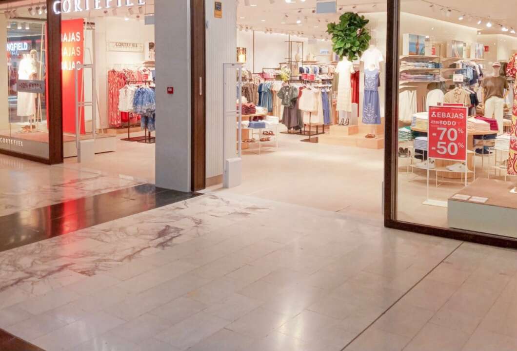 Clothing store in a mall storefront with mannequins and racks of clothes, plus red sale signs offering 70% and 50% off.
