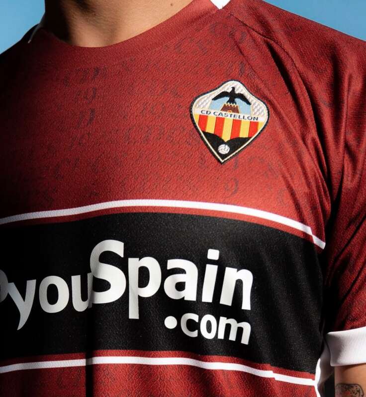 Close-up of a red football jersey showing the CD Castellón crest on the chest and a large 'youSpain.com' sponsor logo beneath.