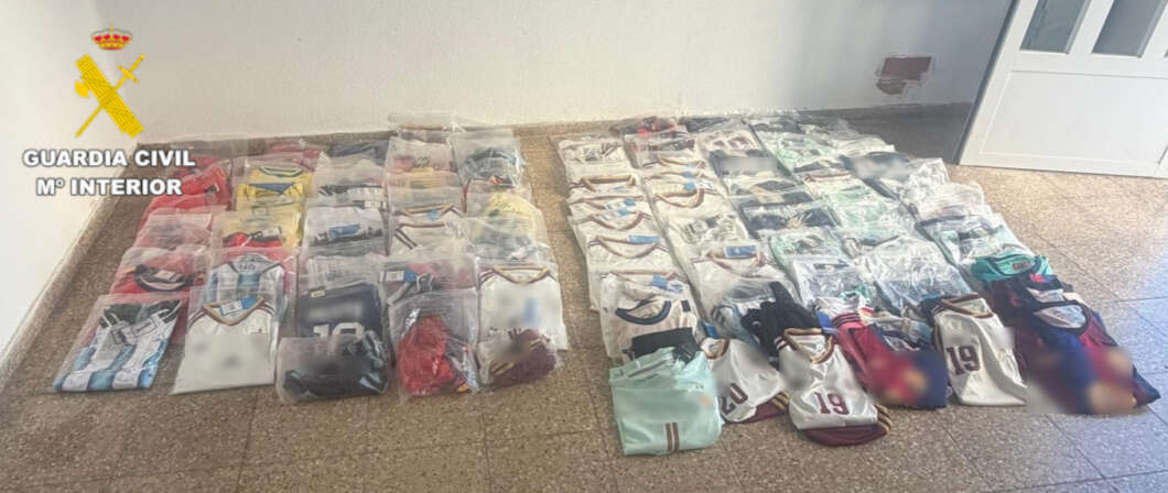 Rows of folded sports jerseys laid out on a tiled floor; Guardia Civil emblem visible in the top-left corner.