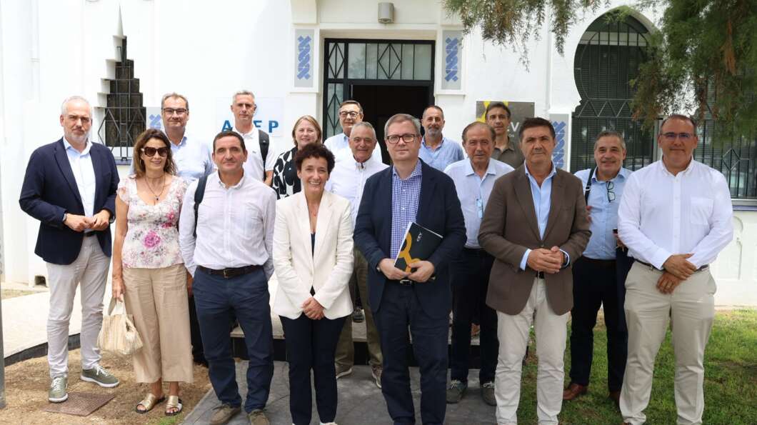 Group of professionals posing for a photo on the steps of a white building in business attire.