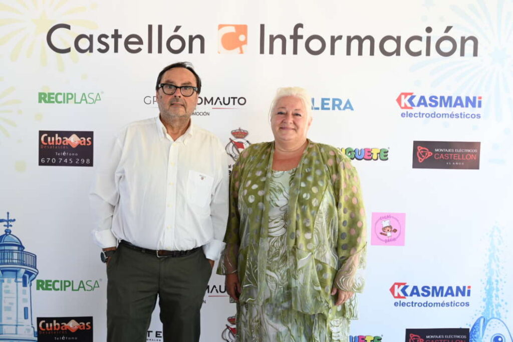 Two adults pose for a photo at a Castellón Información event, standing side by side in front of a sponsor-filled backdrop.