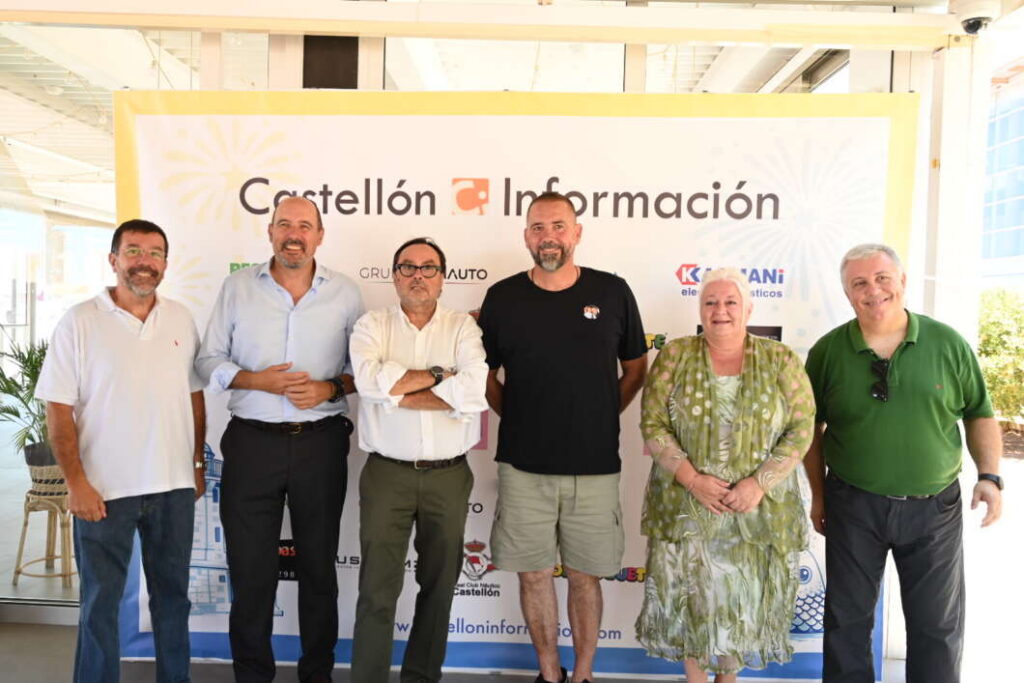 Six adults posing together in front of a Castellón Información banner at an indoor event.