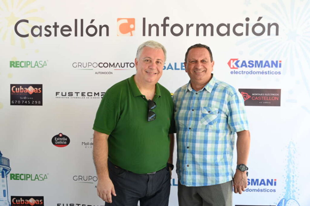 Two smiling men stand side by side in front of a Castellón Información backdrop at an event.