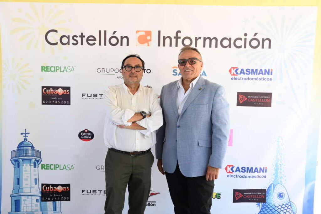 Two men pose for a photo in front of a Castellón Información backdrop with sponsor logos at an event venue.