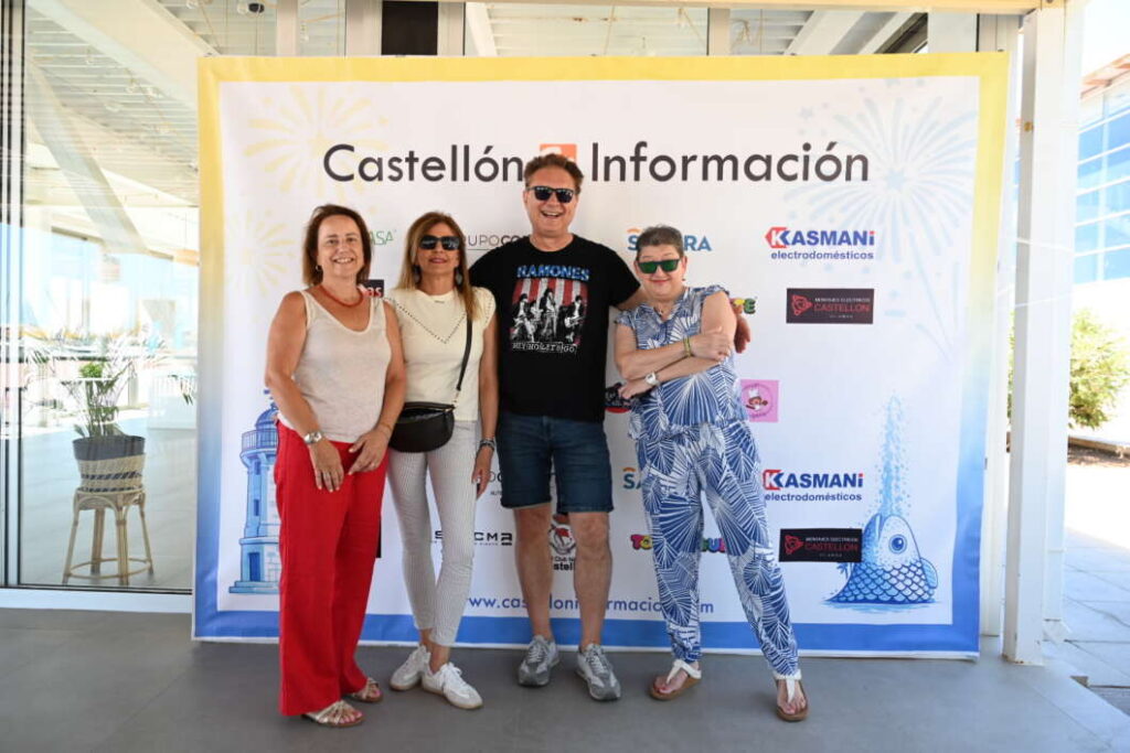 Five adults pose together in front of a Castellón Información banner at an event, smiling and dressed casually in summer clothing.