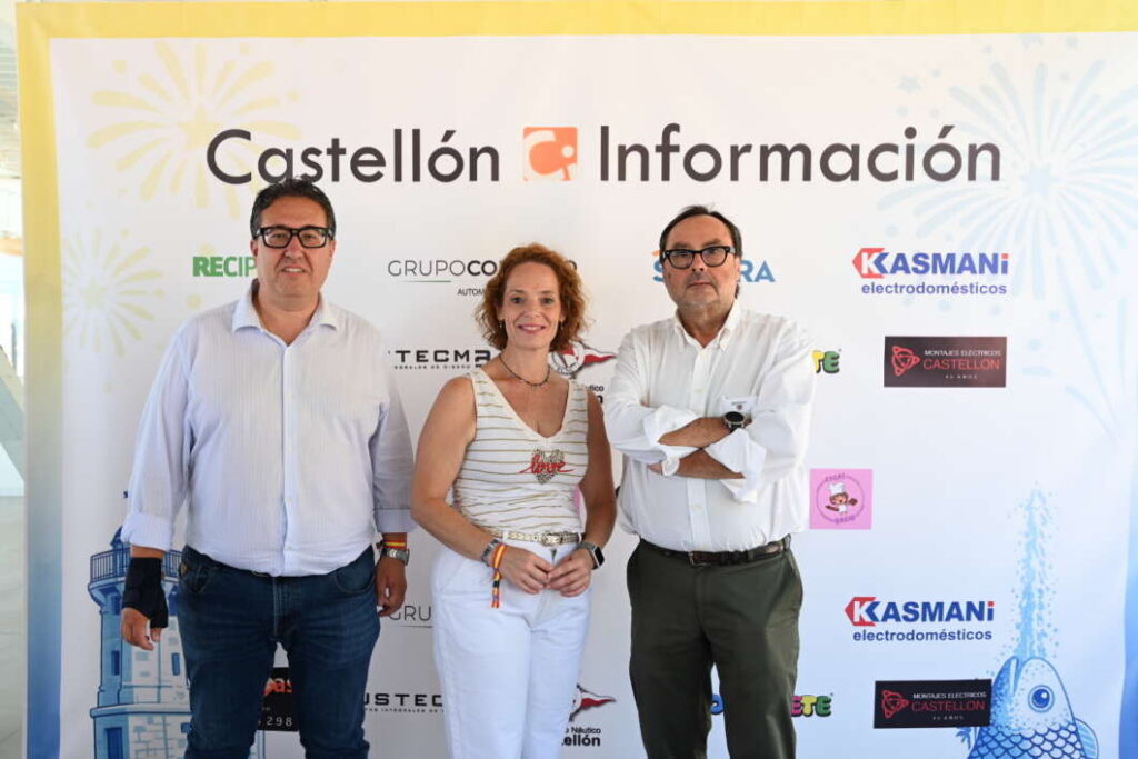 Three adults pose for a photo in front of a Castellón Información backdrop at an event, with sponsor logos visible behind them.