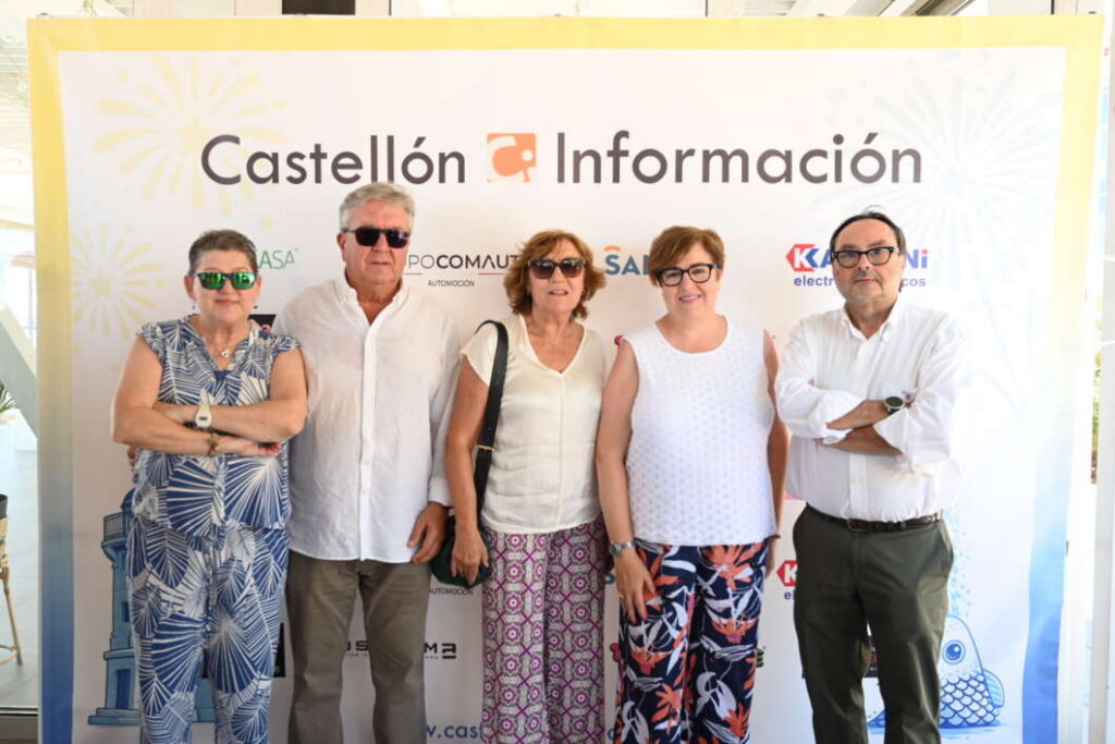 Five adults posing in front of a Castellón Información banner at an event.