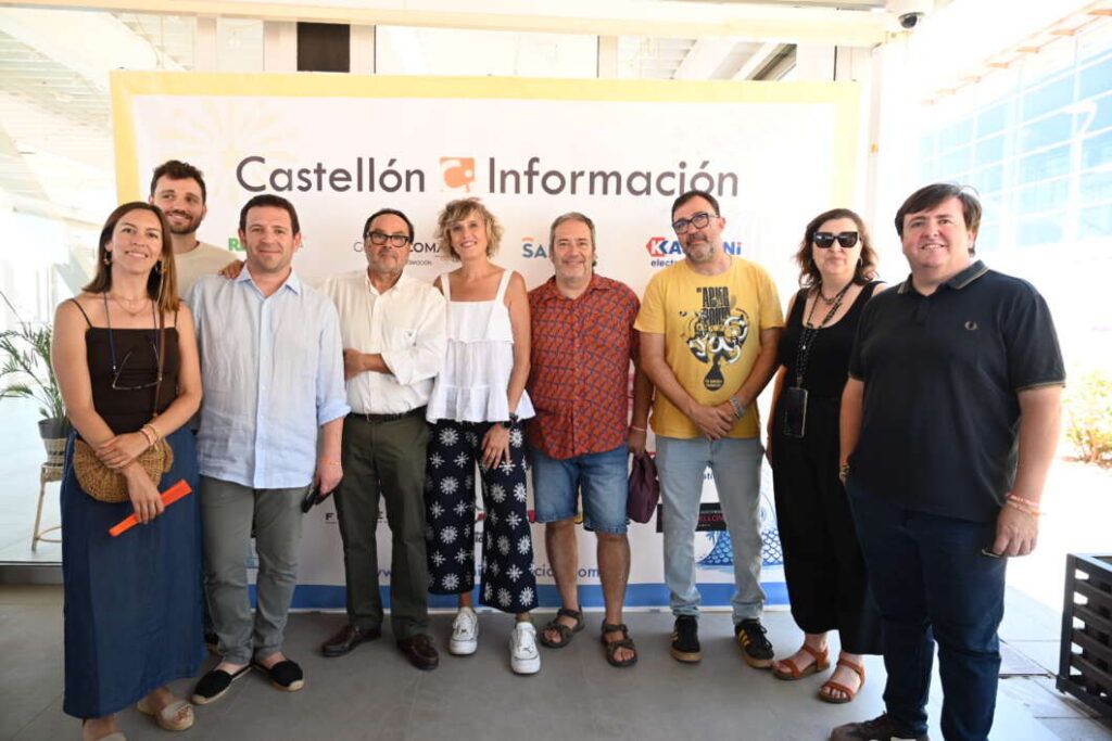 Ten people posing for a group photo in front of a Castellón Información banner at a media event.