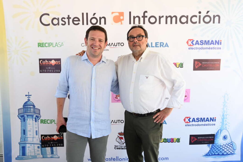 Two men posing and smiling in front of a Castellón Información backdrop with sponsor logos by their sides.