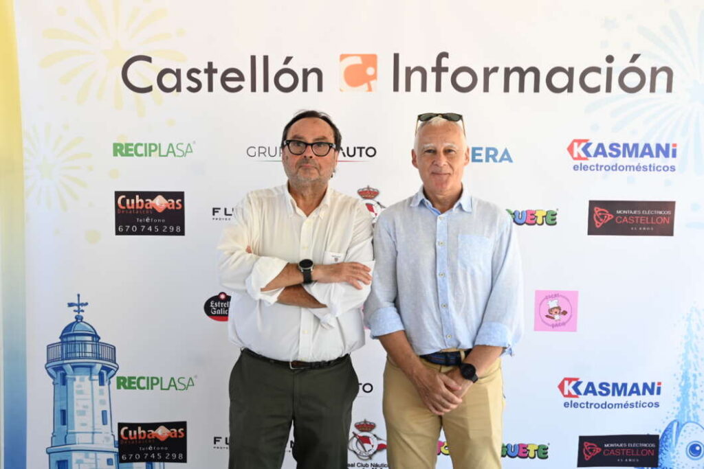Two men stand side by side in front of a Castellón Información backdrop with sponsor logos behind them, posing for a photo.