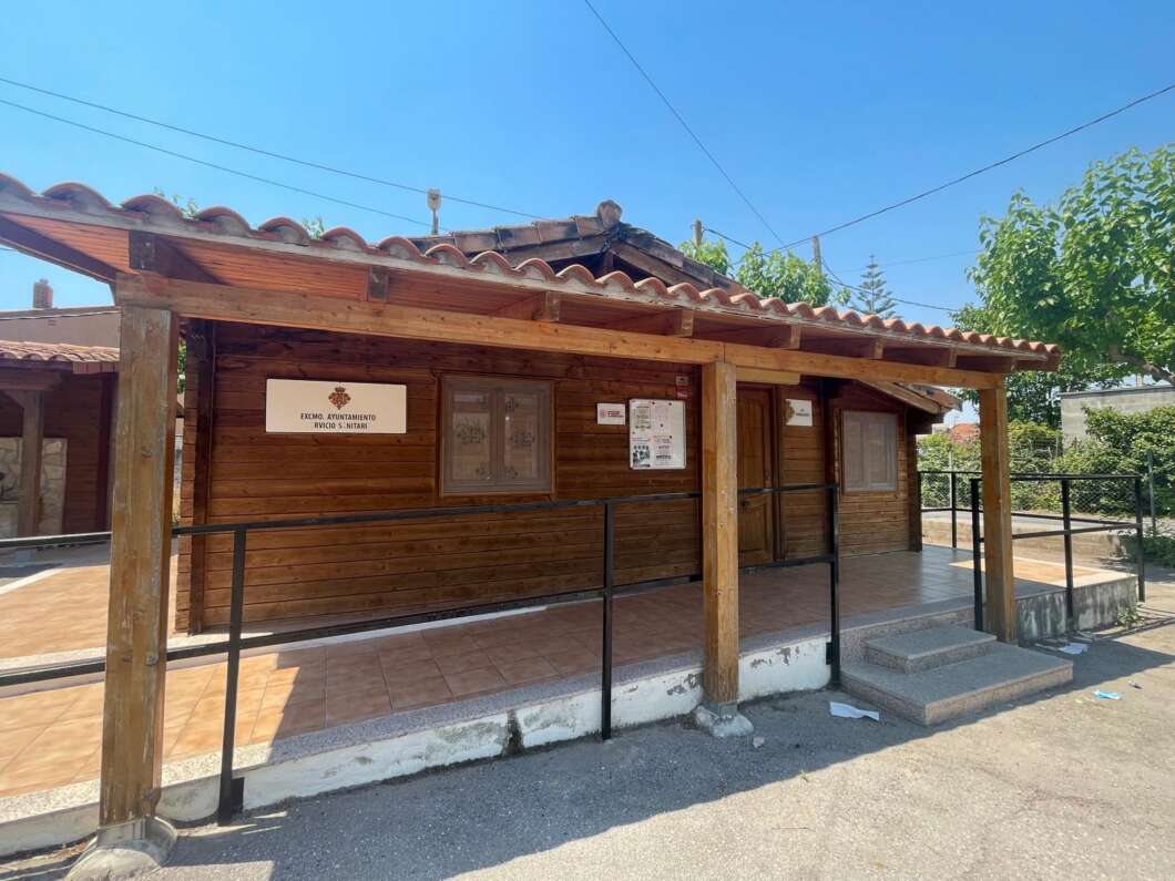 Wooden kiosk with a tiled, sloped roof and a covered porch; signs on the wall and a ramp leading to the entrance.