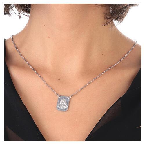Silver chain necklace with a rectangular pendant resting on a woman's décolletage.