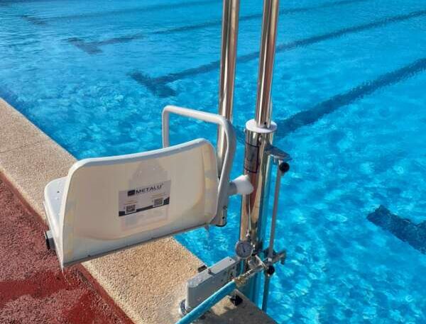 White plastic poolside seat mounted on a metal frame attached to the pool edge, with bright blue water in the background.