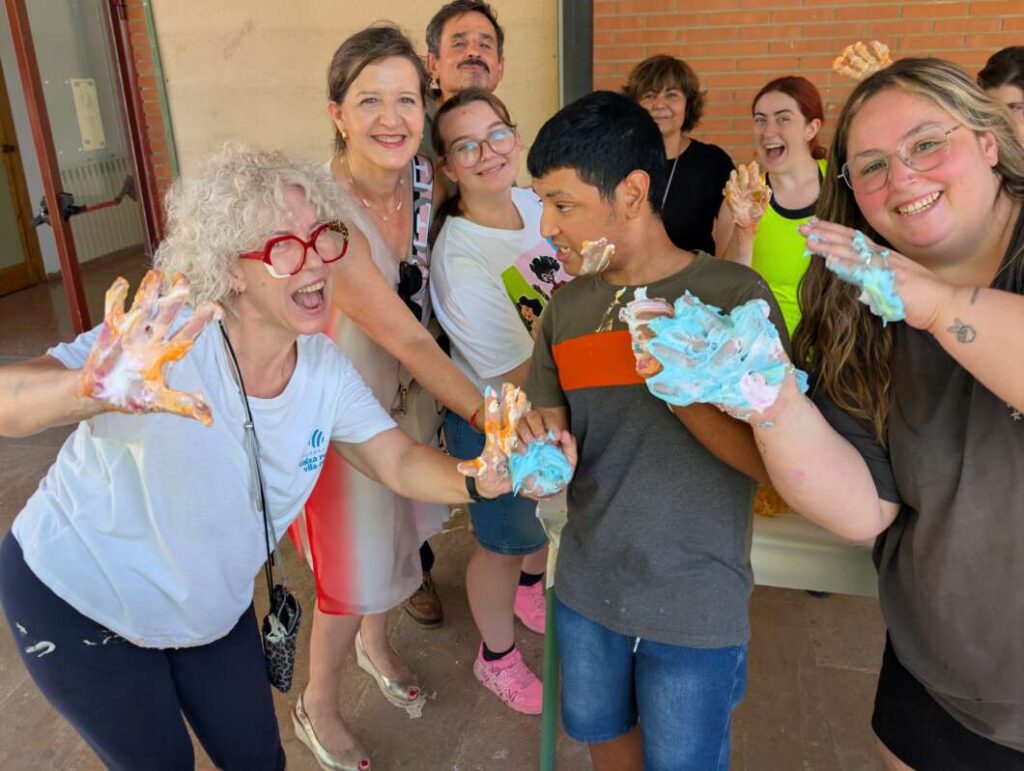 Smiling group of people with painted hands posing together outdoors after a community art activity.